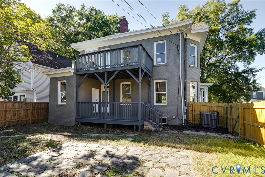 Painted brick exterior featuring a two-story wood deck, flagstone patio, and fenced yard