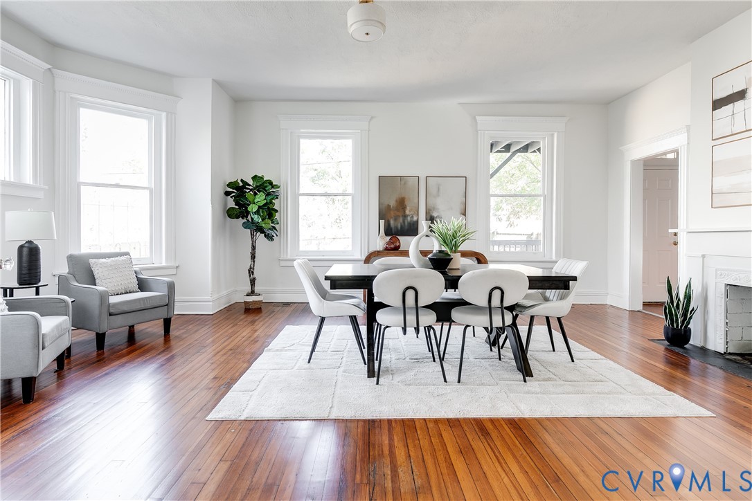 Interior space featuring wood-finish flooring, bay windows, a decorative fireplace surround, and ceiling-mounted light fixture