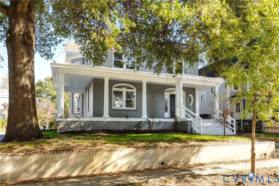 Two-story exterior featuring a wraparound porch, classical columns, arched window detailing, and a concrete retaining wall Two-story exterior featuring a wraparound porch, classical columns, arched window detailing, and a concrete retaining wall