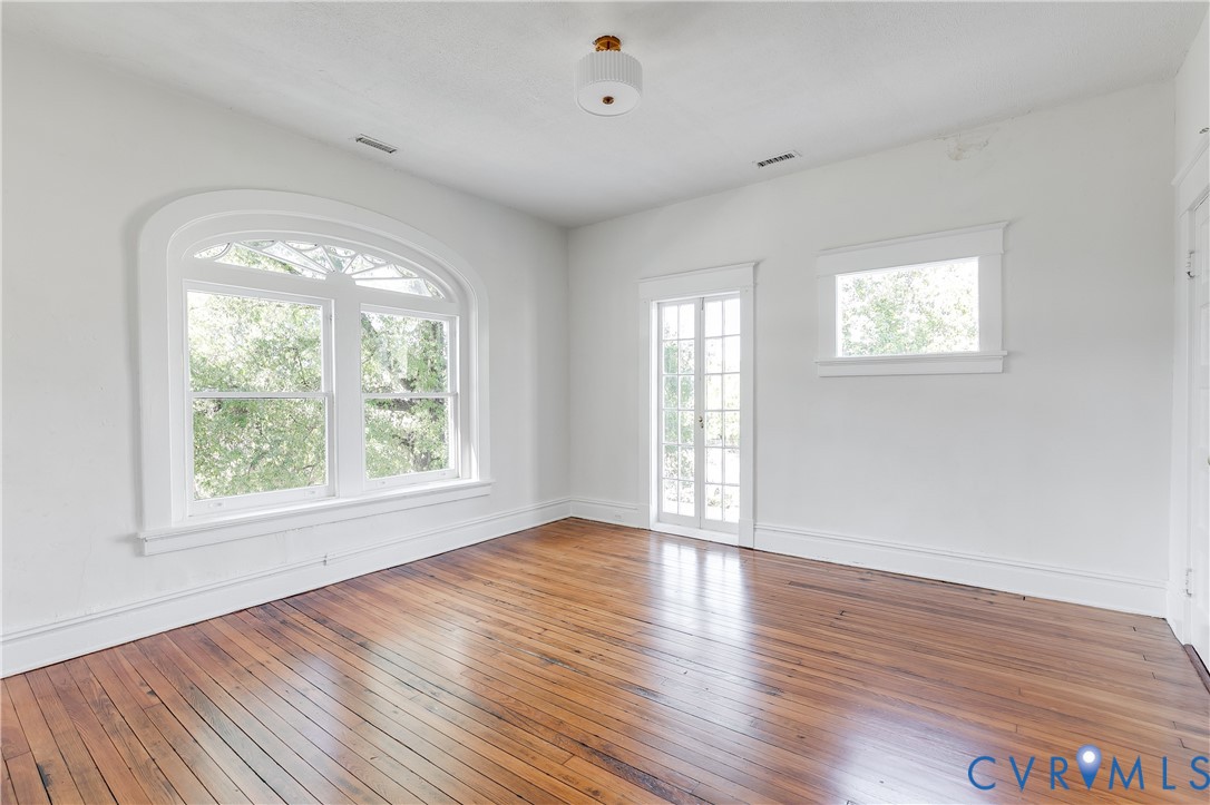 Wood-finish flooring, arched multi-pane window, French door with sidelights, and overhead semi-flush mount lighting
