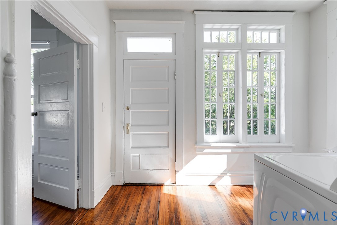 Original wood-finish flooring, multi-pane casement windows, five-panel interior door with transom window, and architectural millwork trim