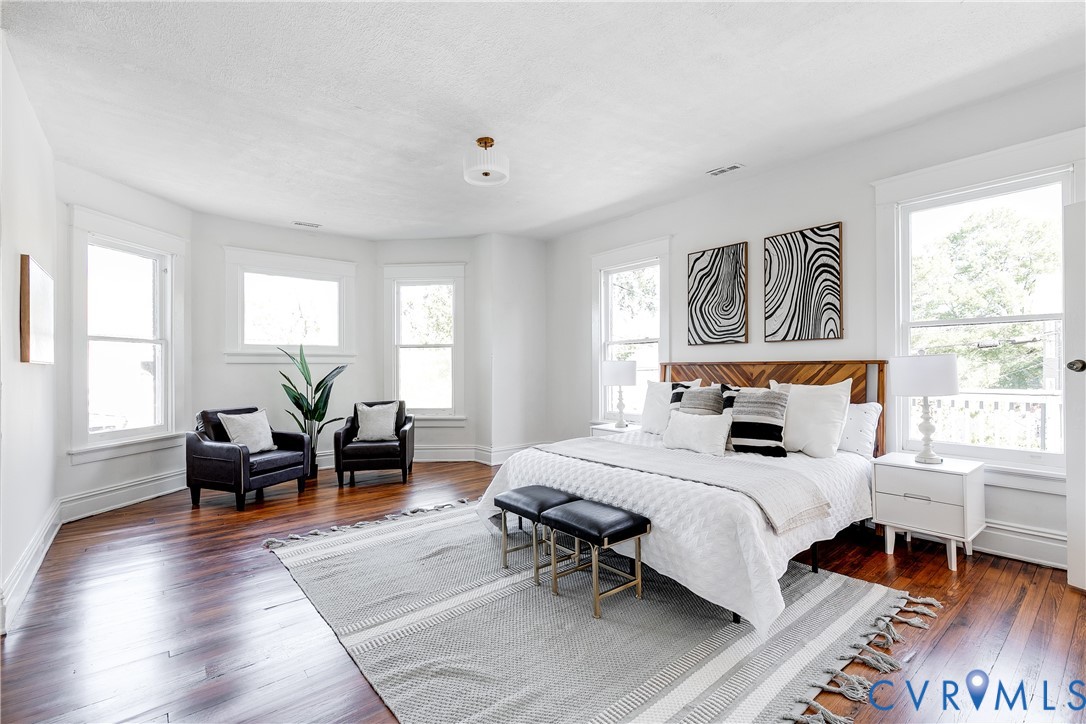 Spacious room featuring wood-finish flooring, a bay window configuration, and an overhead flush-mount light fixture