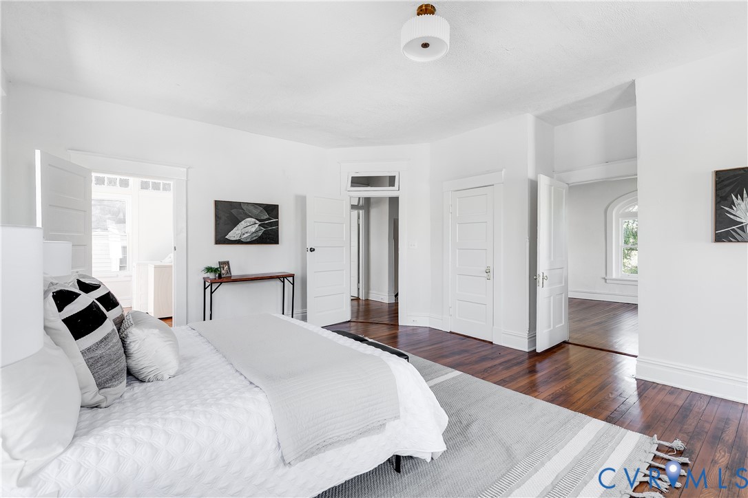 Polished dark wood-finish flooring, multi-panel interior doors, crisp white walls, and a modern drum ceiling fixture