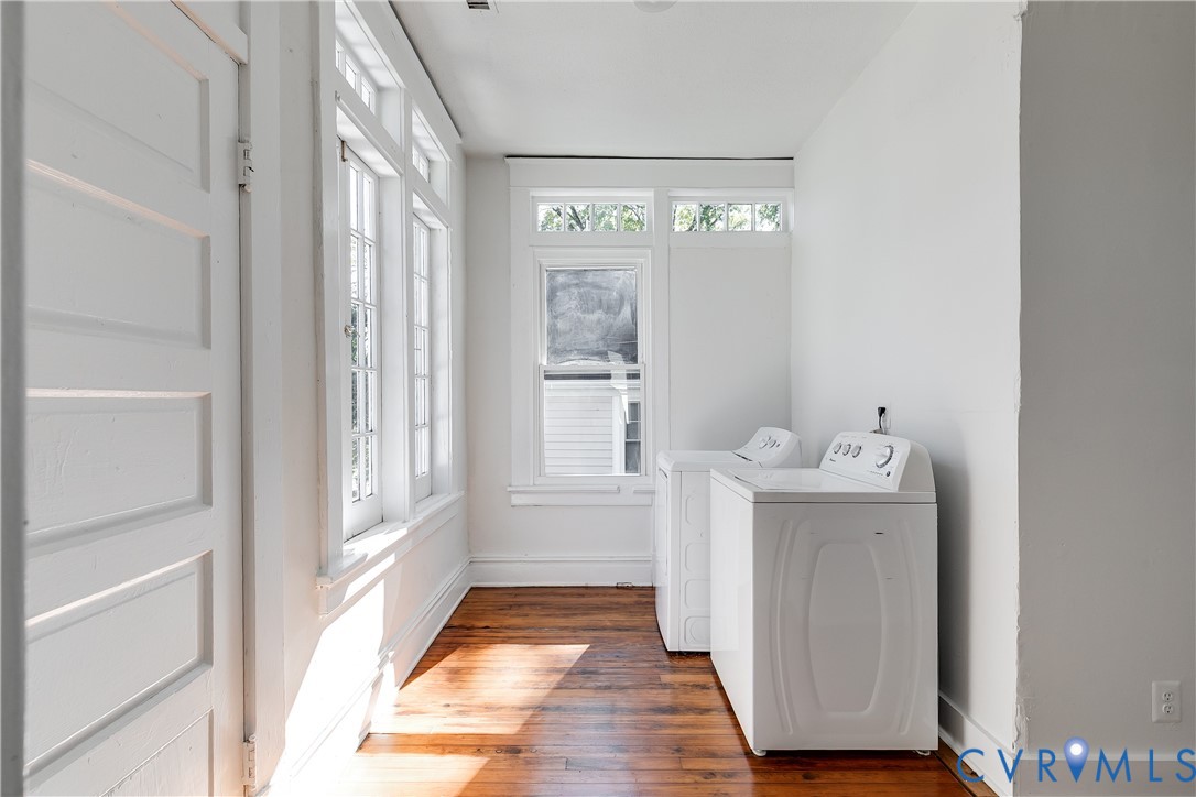 Laundry area featuring wood-finish flooring, extensive multi-pane windows with transoms, and high ceilings