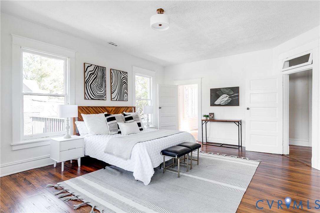 Interior space featuring wood-finish flooring, white paneled doors, traditional casing, and a flush-mount drum light fixture