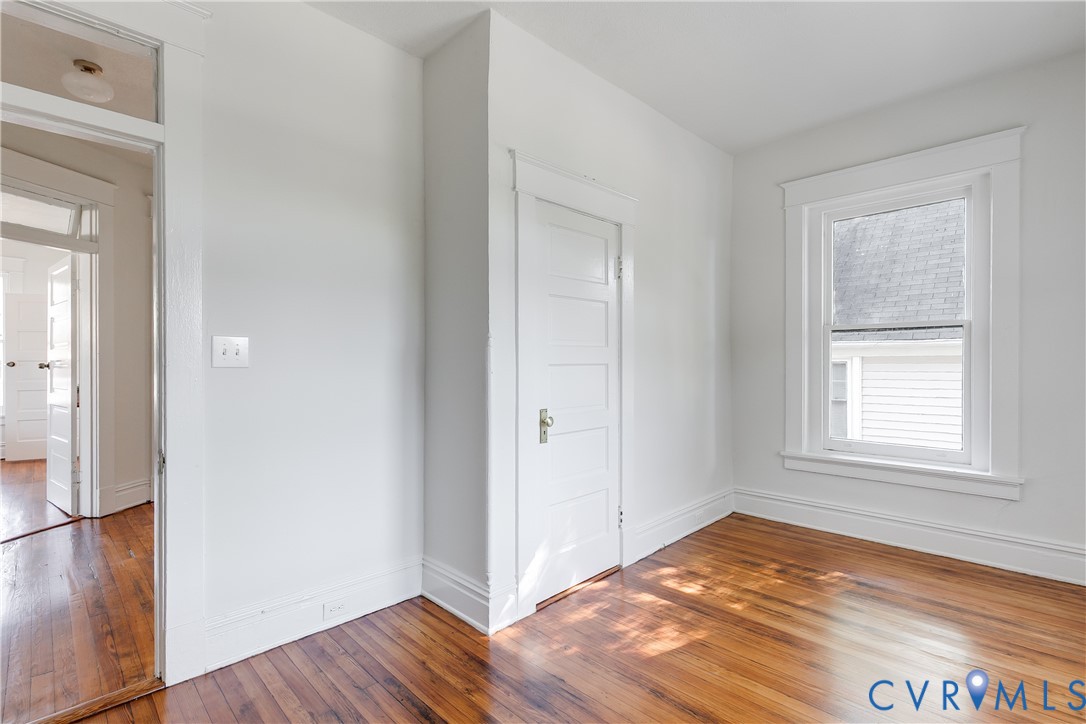 Polished wood-finish flooring, five-panel interior door, traditional window casing, and transom window detail