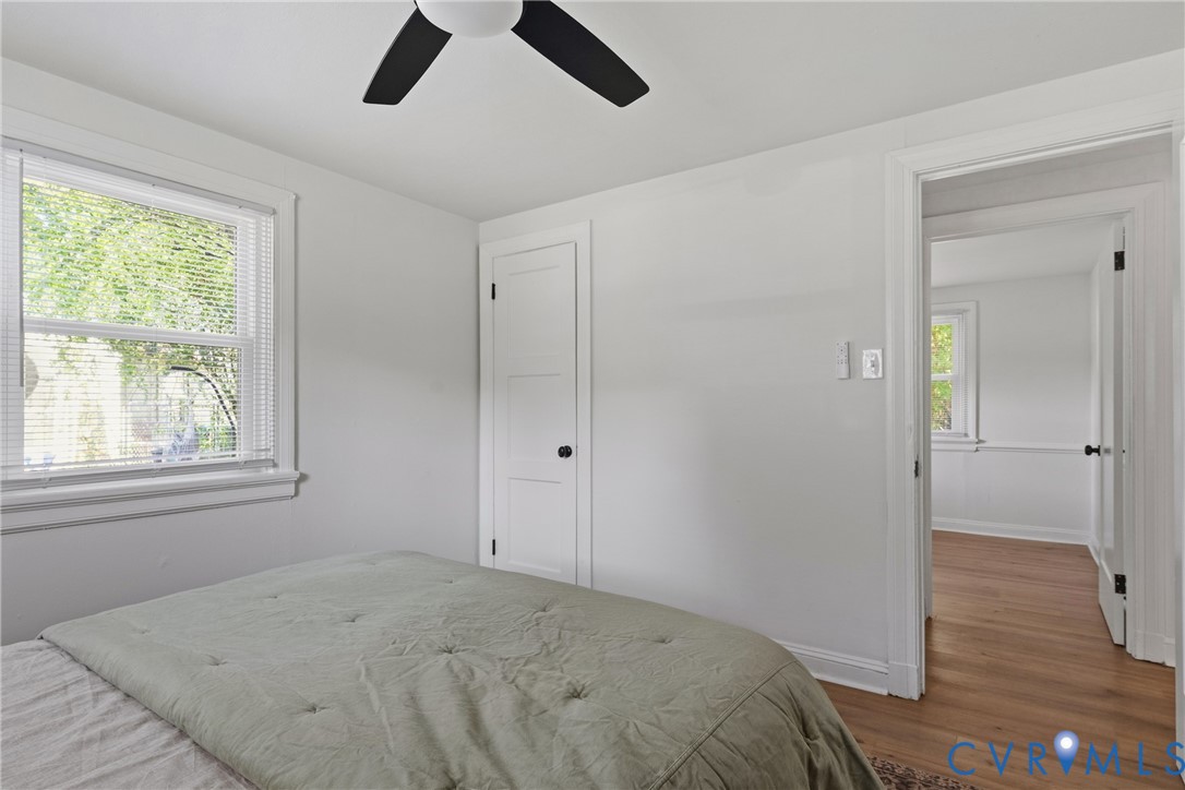 White walls, a ceiling fan, and a light wood-finish flooring