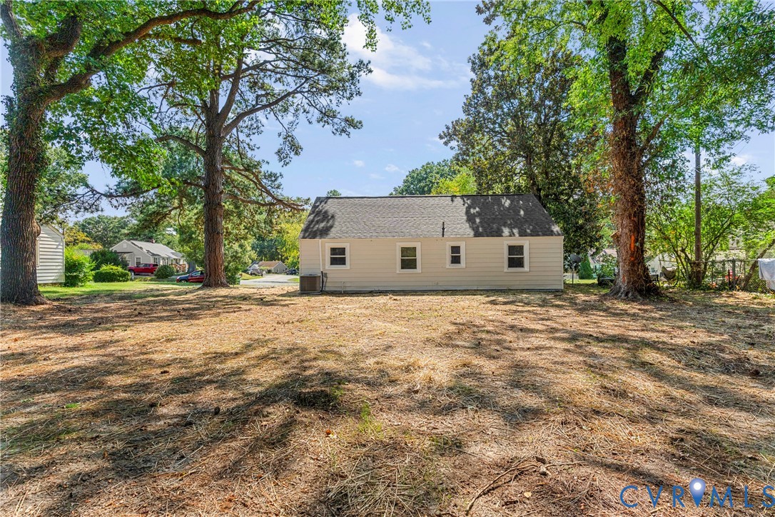 Expansive rear yard featuring mature trees and a detached shed