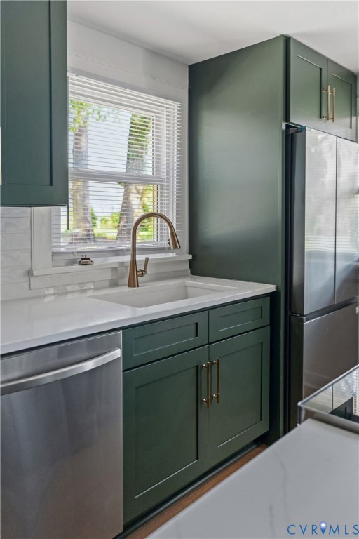Kitchen with contemporary green cabinetry, white countertops, stainless steel appliances, and a white subway tile backsplash