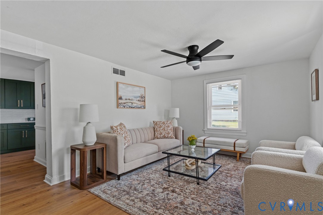 Bright living area with wood-finish flooring, a contemporary ceiling fan, and white walls Bright living area with wood-finish flooring, a contemporary ceiling fan, and white walls