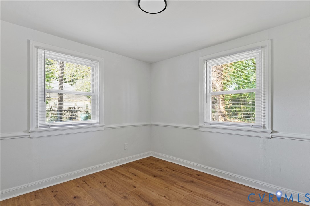 Wood-finish flooring, white walls, two double-hung windows, and a ceiling-mounted light fixture