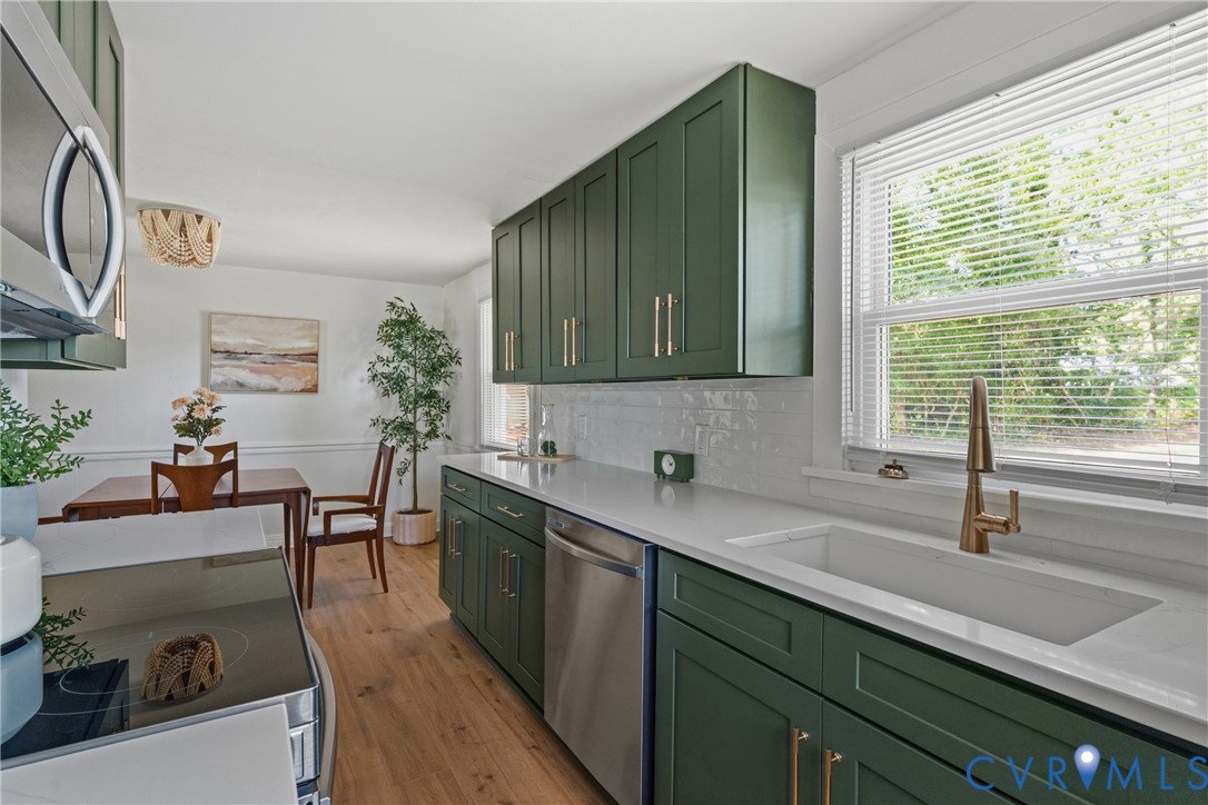 Kitchen featuring green cabinetry with gold-tone hardware, white countertops, subway tile backsplash, and wood-finish flooring