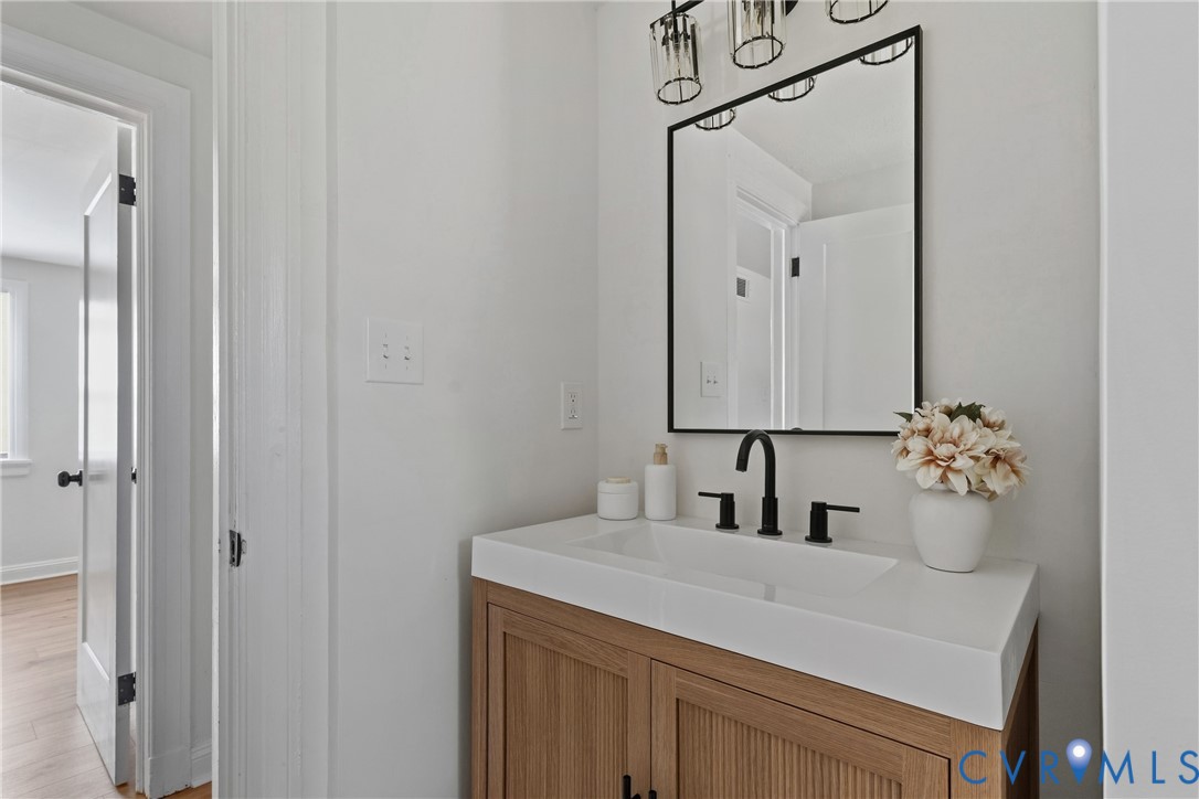 Bathroom vanity with a white countertop and integrated sink, featuring a matte black faucet