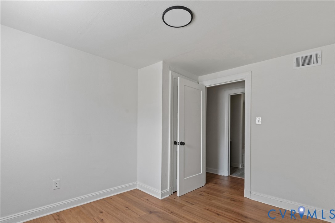 Wood-finish flooring, white trim, recessed lighting, and a solid core door with matte black hardware