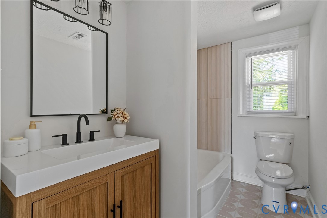 Wood-finish vanity with white integrated sink, matte black faucet, and rectangular mirror