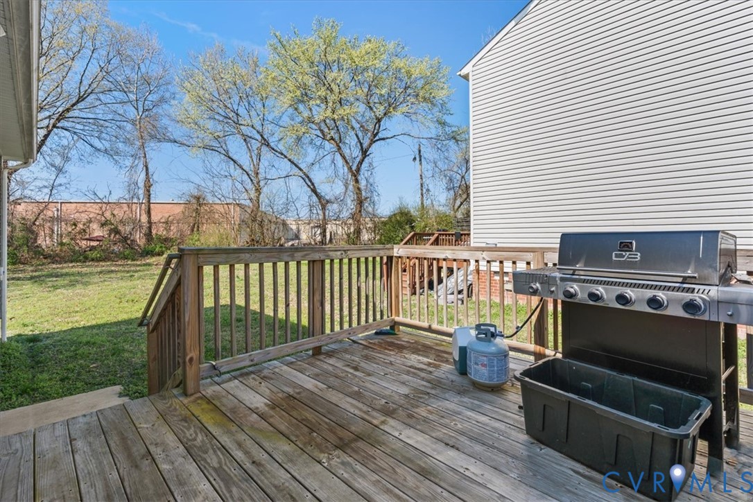 Rear wooden deck featuring horizontal planking, vertical wood railing, and stair access to the grounds