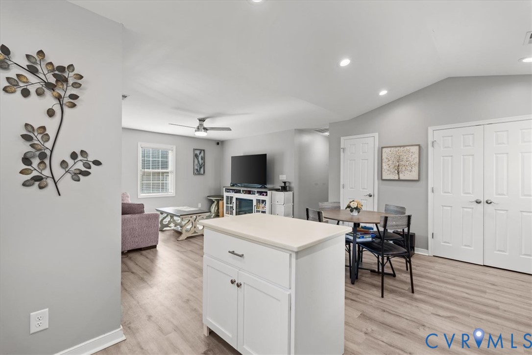 Vaulted ceilings, wood-finish flooring, recessed lighting, white cabinetry, and double-panel doors