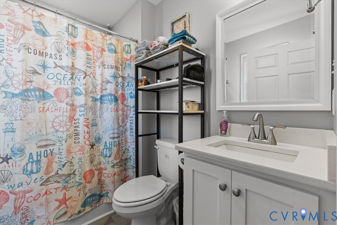 Bathroom featuring a white vanity cabinet, solid-surface countertop with an integrated rectangular sink, dual-handle metal faucet, and a large wall-mounted mirror with a white frame