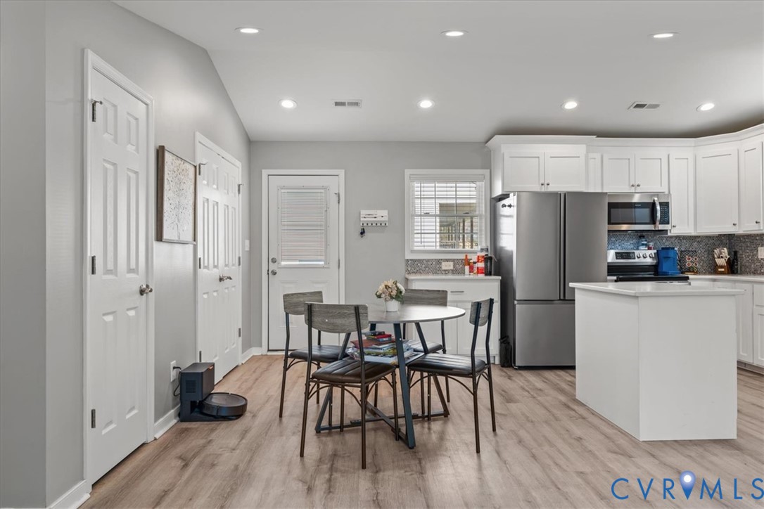 Kitchen featuring white cabinetry, stainless steel appliances, a central island, recessed lighting, and wood-finish flooring