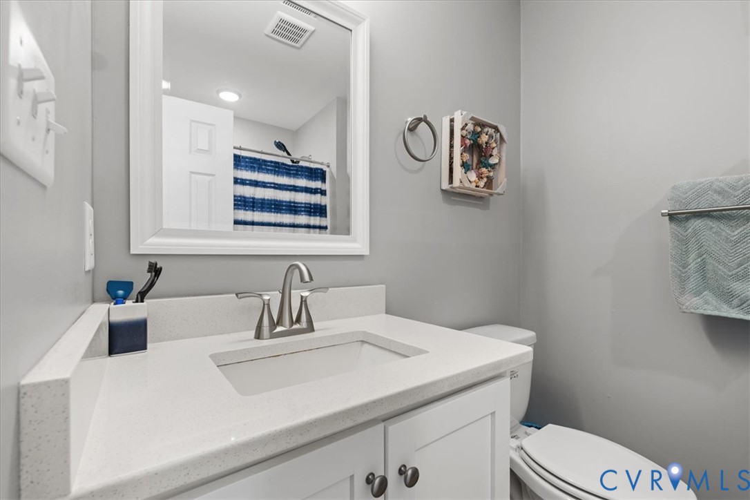 White vanity cabinet featuring a quartz countertop with an integrated rectangular sink and brushed nickel faucet, paired with a framed wall mirror