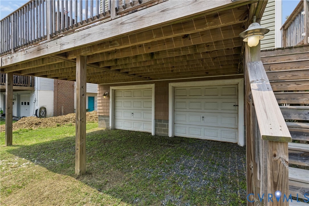 Two-car garage featuring paneled doors and an exterior wooden deck with a staircase