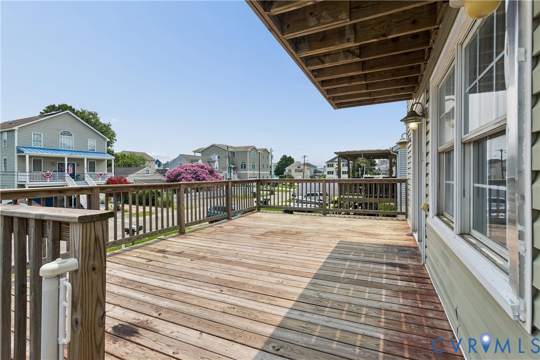 Elevated wood deck featuring a wooden railing and wall-mounted exterior lighting