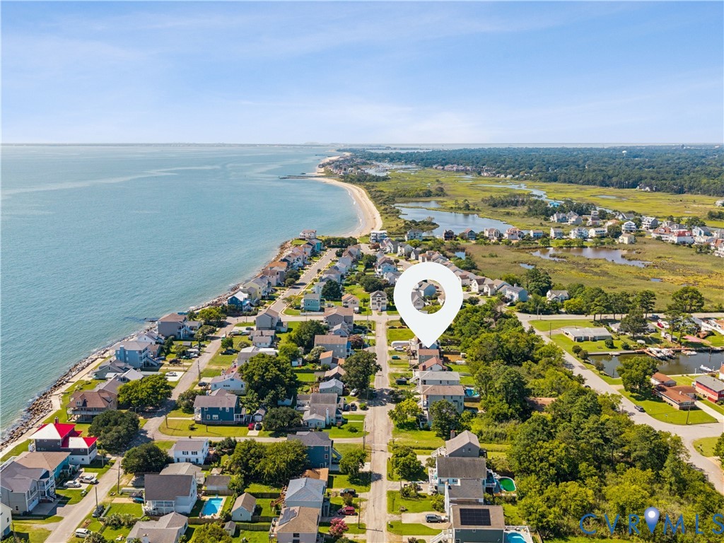 Aerial perspective of residential coastal property featuring proximity to the shoreline, surrounding salt marsh ecosystems, and paved street access Aerial perspective of residential coastal property featuring proximity to the shoreline, surrounding salt marsh ecosystems, and paved street access