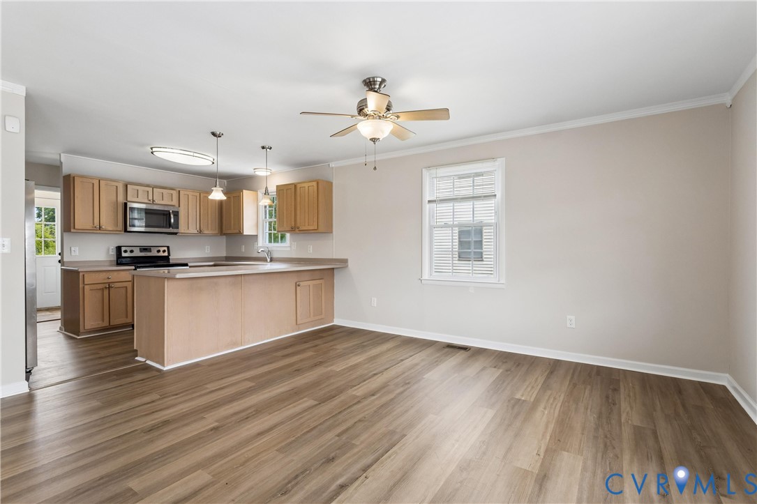 Kitchen featuring wood-finish cabinetry, a peninsula, stainless steel appliances, and wood-finish flooring throughout the space Kitchen featuring wood-finish cabinetry, a peninsula, stainless steel appliances, and wood-finish flooring throughout the space