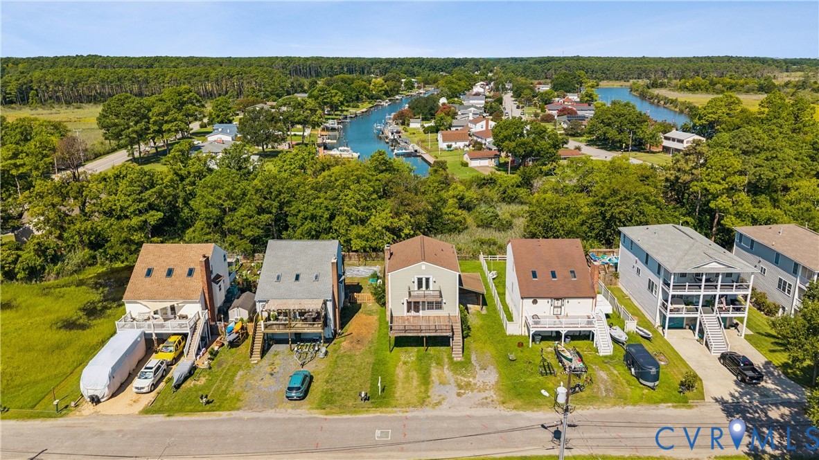 Aerial perspective of waterfront properties featuring direct canal access, elevated multi-level decks, exterior staircase entryways, and asphalt shingle roofing