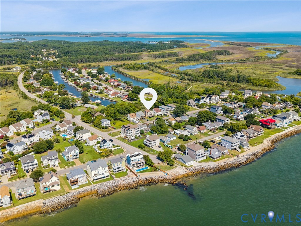 Aerial perspective of a coastal property featuring direct water frontage, a private outdoor swimming pool, multi-level exterior decking, and proximity to natural salt marshes