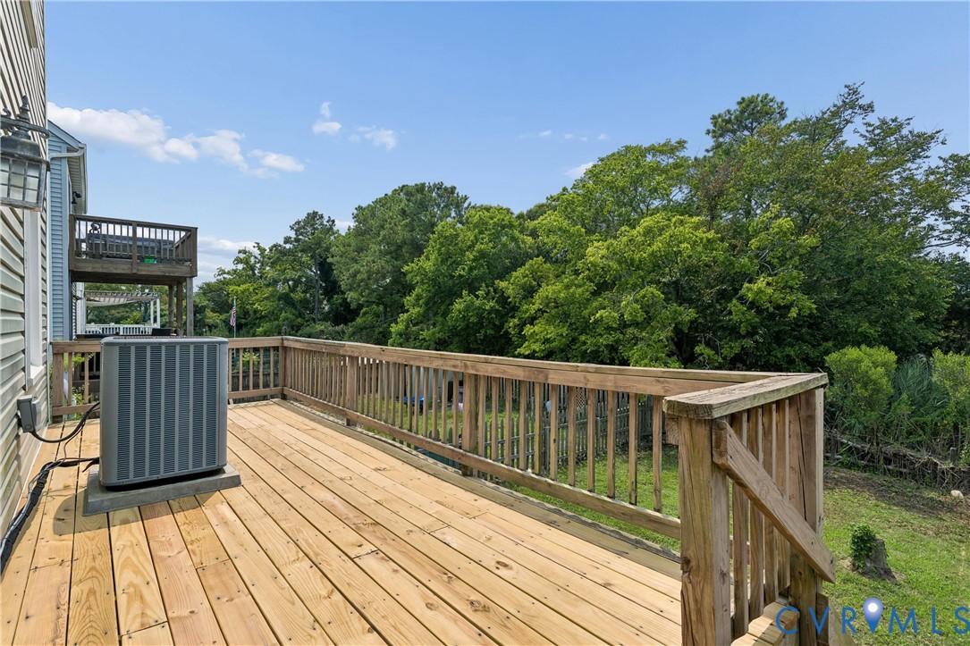 Elevated wood deck featuring vertical wood balustrades and a secondary upper-level balcony