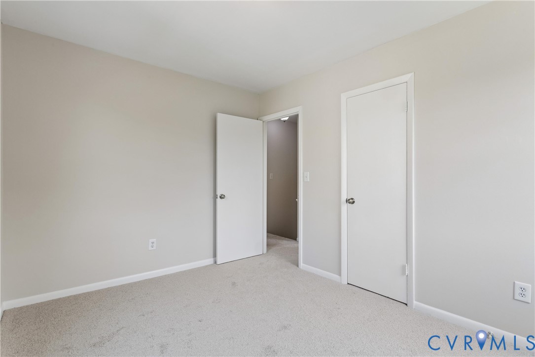 Neutral interior room featuring neutral-toned walls, carpeted flooring, and two interior doors with brushed nickel hardware
