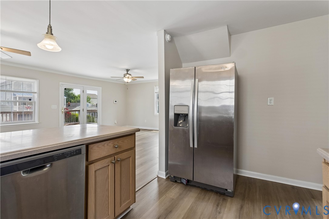 Kitchen featuring stainless steel appliances, wood-finish cabinetry, neutral wall paint, wood-finish flooring, and recessed ceiling fans
