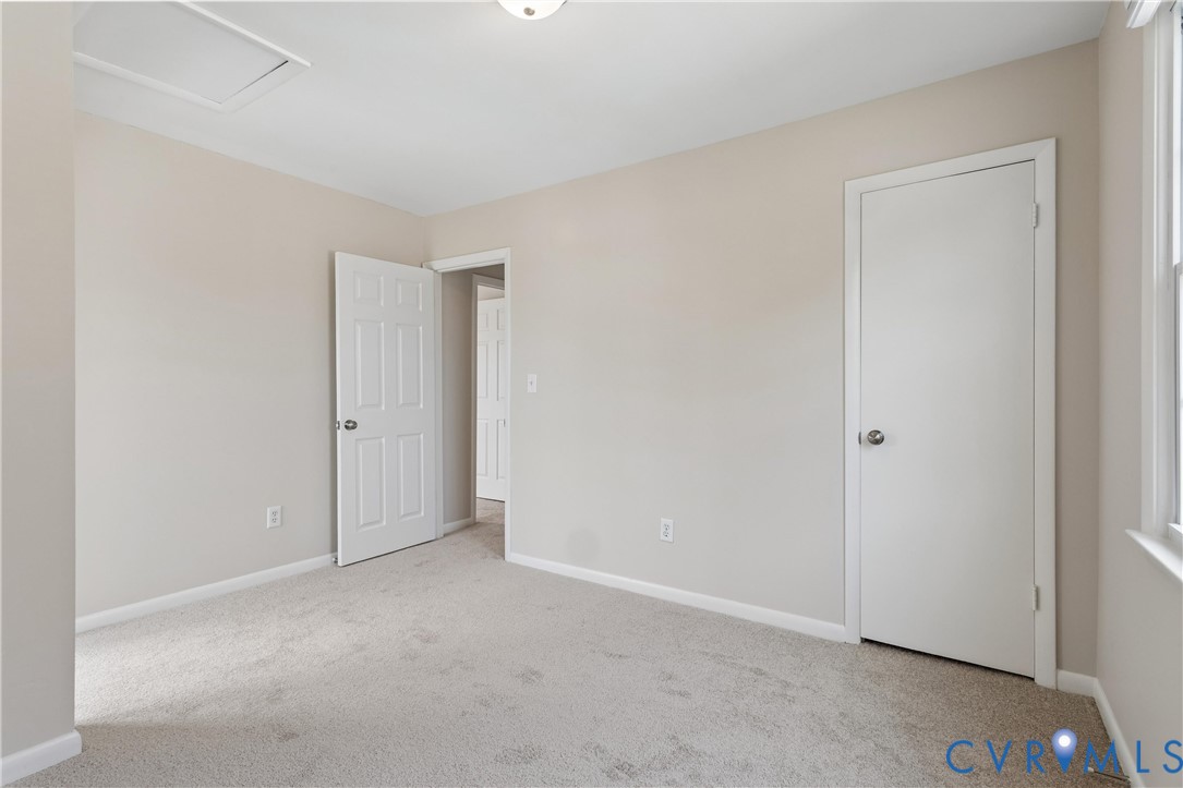 Neutral-toned interior featuring wall-to-wall carpeting, white six-panel interior doors, and a ceiling access panel