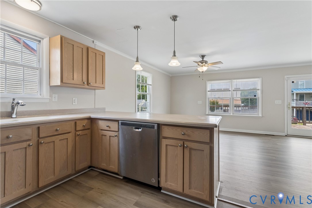 Kitchen featuring wood-finish cabinetry, stainless steel dishwasher, dual pendant lighting, and wood-finish flooring