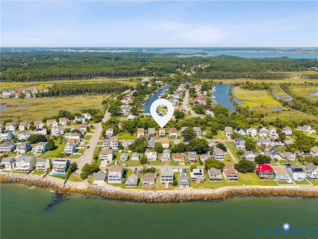 Aerial perspective of coastal residential property featuring waterfront positioning, established tree canopy, and proximity to tidal waterways