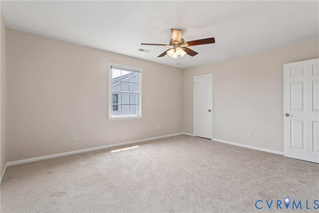 Neutral-toned interior featuring wall-to-wall carpeting, a multi-blade ceiling fan with integrated lighting, and six-panel doors