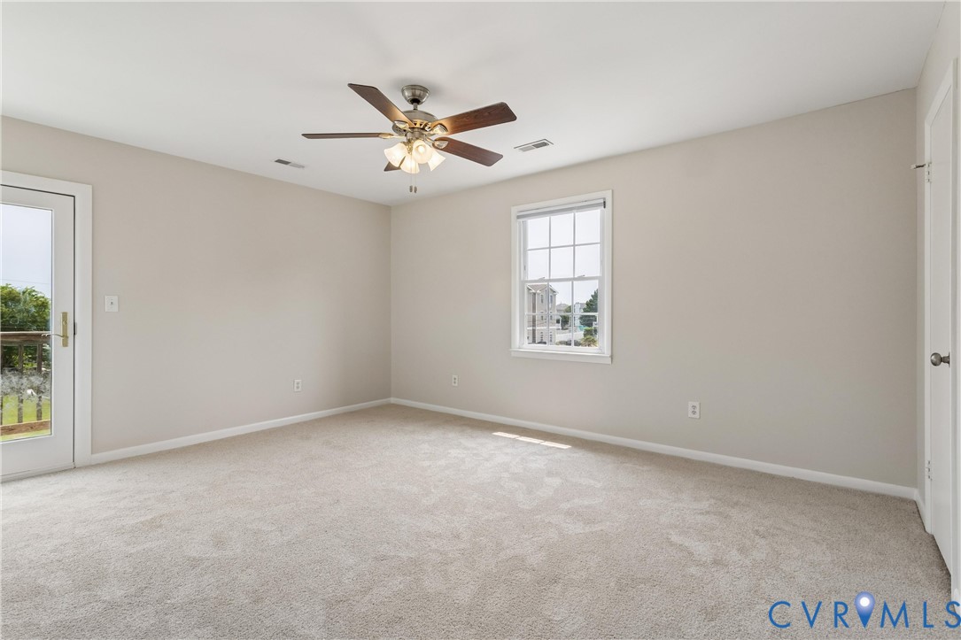 Neutral-toned interior featuring wall-to-wall carpeting, a multi-light ceiling fan, a single-hung window with muntins, and a glass-paneled exterior door