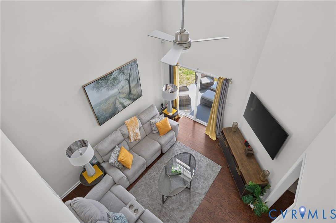 Two-story living area featuring vaulted ceilings, wood-finish flooring, a ceiling fan, and sliding glass doors to the exterior