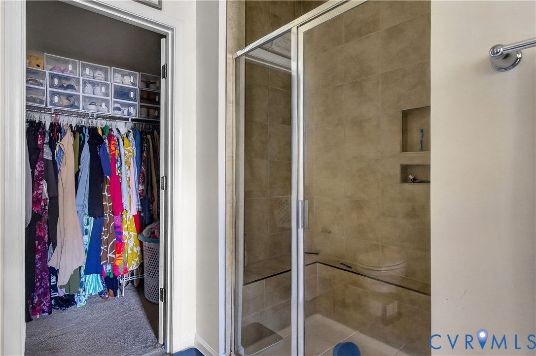 Walk-in closet featuring wire shelving and a glass-enclosed shower with tile surround, built-in bench seating, dual wall niches, and polished chrome hardware