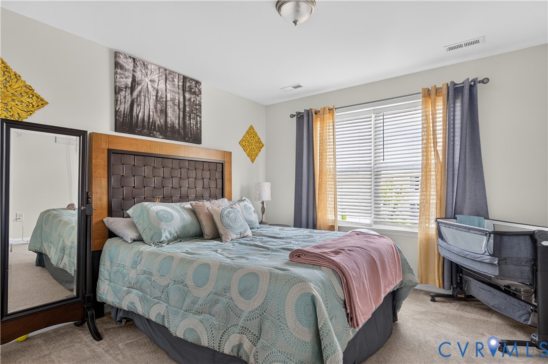 Bedroom featuring neutral-toned carpeting, a horizontal sliding window, and a flush-mount ceiling light fixture