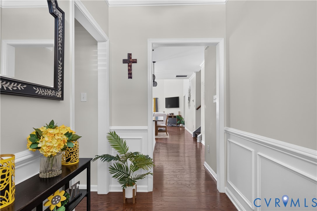 Foyer featuring wood-finish flooring, white wainscoting, and crisp white door trim