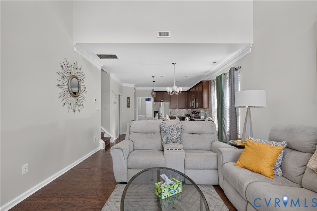 Vaulted ceilings, dark wood-finish flooring, crown molding, and recessed lighting