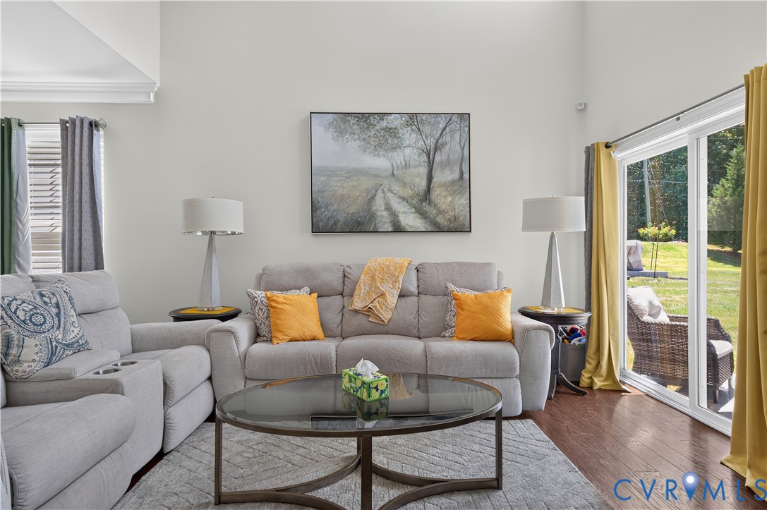 Vaulted ceilings, dark wood-finish flooring, and sliding glass doors with outdoor access