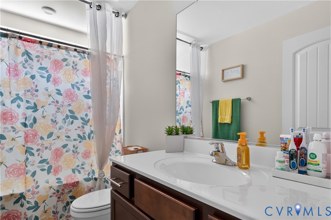 Bathroom featuring a vanity with a white countertop and integrated sink, polished chrome faucet, large wall-mounted mirror, and a built-in bathtub