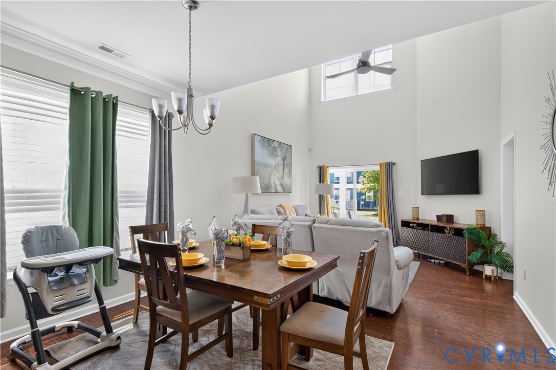 Vaulted ceiling featuring a ceiling fan, crown molding, wood-finish flooring, and multi-paned windows