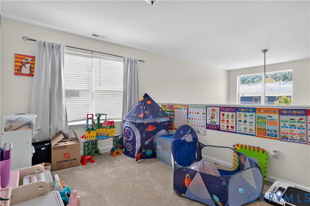 Spacious interior featuring neutral wall tones, wall-to-wall carpeting, multiple windows, and a partial knee wall with a decorative ledge
