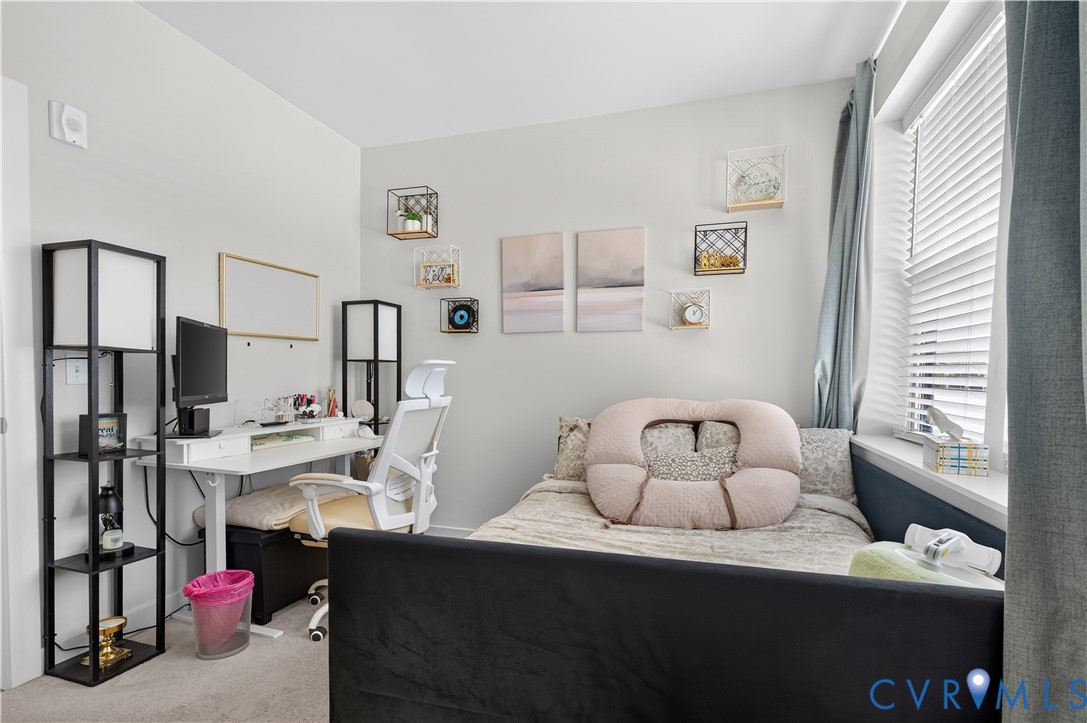 Neutral-toned interior space featuring wall-to-wall carpeting and a window with horizontal blinds