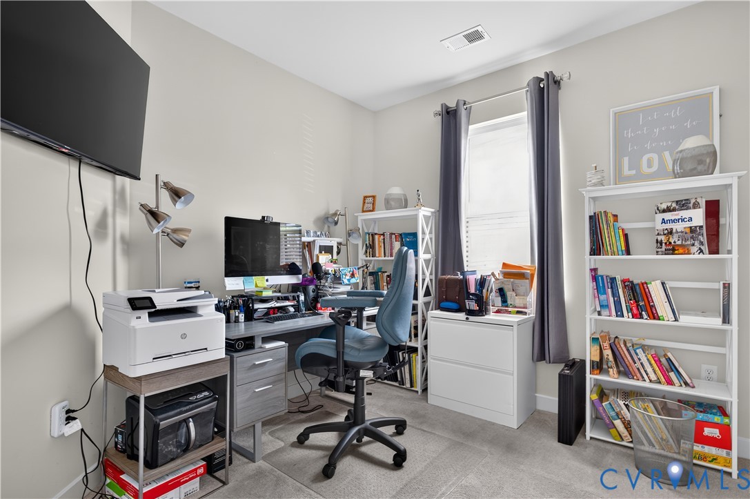 Neutral-toned walls, neutral carpeting, and a single-pane window with a curtain rod