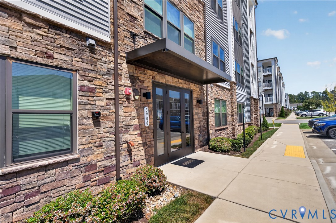 Exterior featuring stone veneer facade, metal-framed glass double-door entrance, and a modern metal cantilevered awning